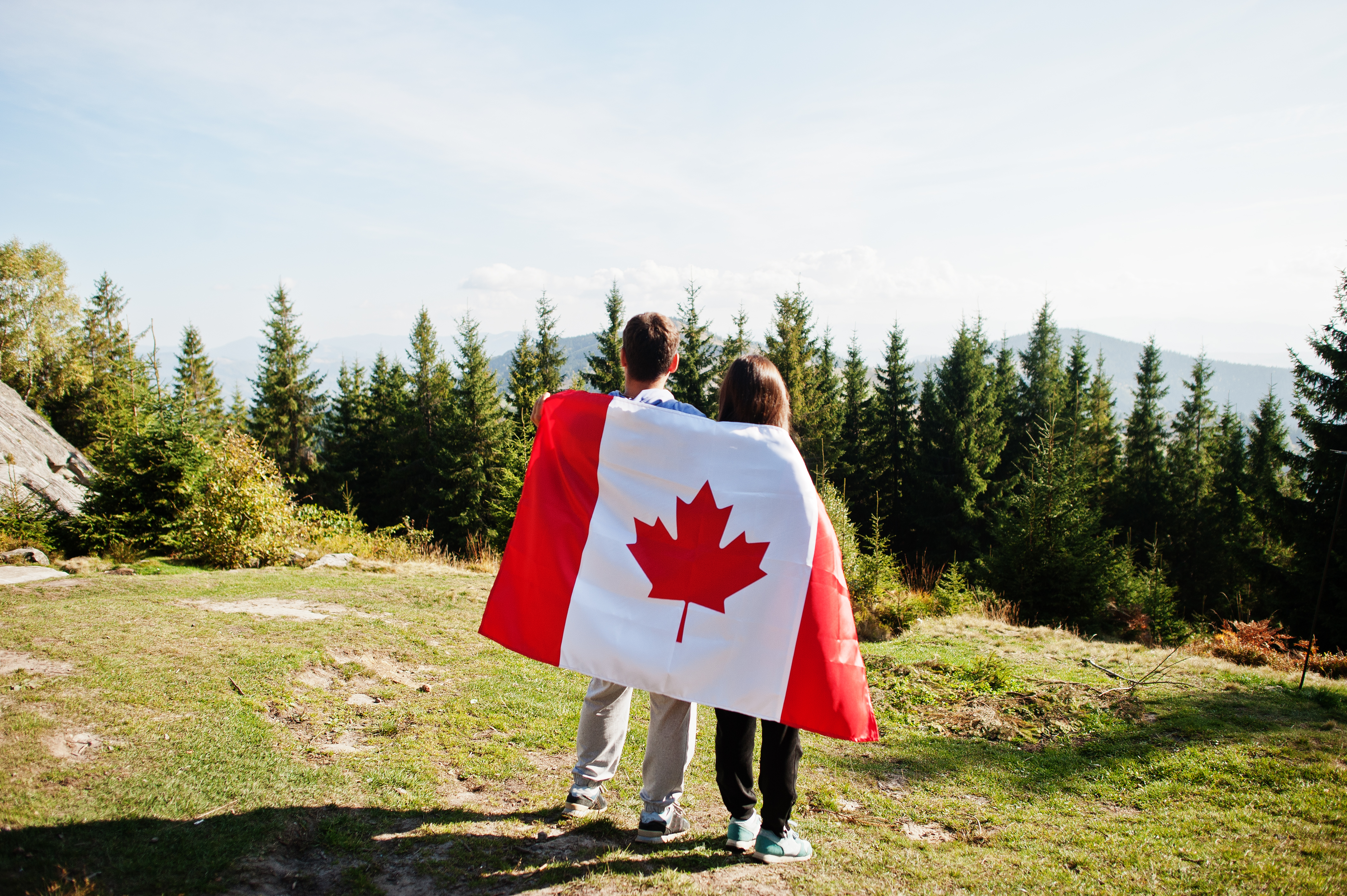 Парень и девушка с канадских флагом в лесу