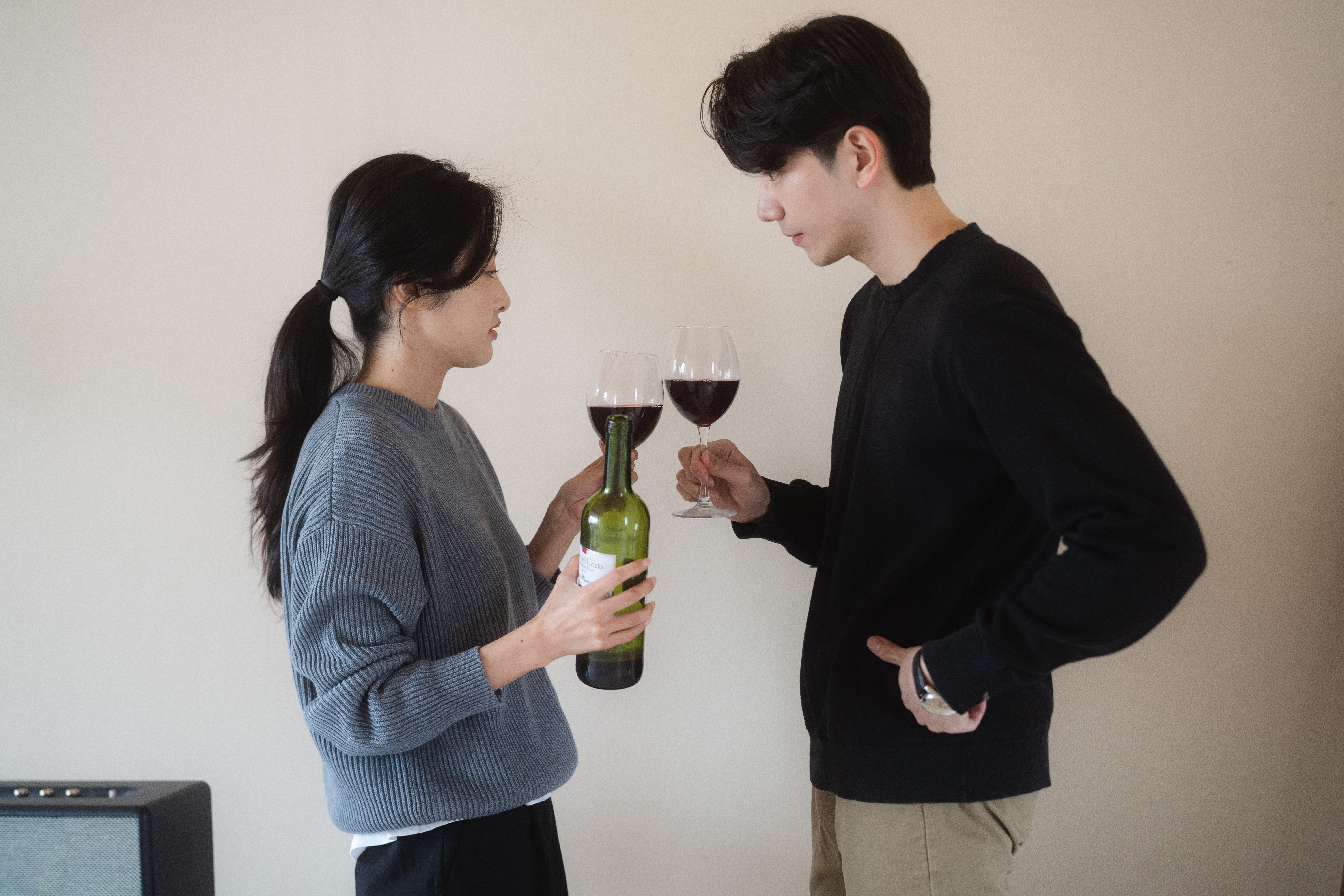 Корейские парень и девушка пьют вино дома